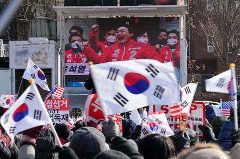 A TV screen shows a file image of South Korean President Yoon Suk Yeol as supporters of impeached Yoon stage a rally to oppose his impeachment near the presidential residence in Seoul, South Korea, Tuesday, Jan. 7, 2025. 