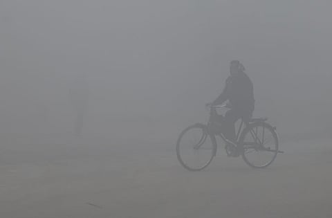 A man rides a bicyle amid dense fog in Delhi on January 15, 2025. 