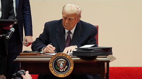 President Donald Trump signs an executive order at an indoor Presidential Inauguration parade event in Washington, Monday,