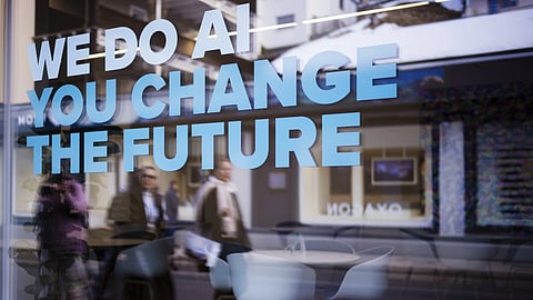 People reflected in a window with a slogan about AI at a representation of a company ahead of the World Economy Forum in Davos, Switzerland, Sunday, Jan 19, 2025.