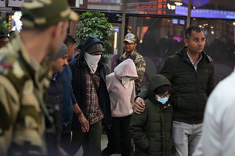 Indian police officials escort immigrants, wearing mask, deported from the United States, who were among those who arrived in a U.S. military plane.