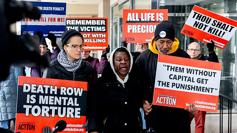 Lizz Schallert, left, and Charles Keith, right, stand in solidarity with Carol Frazier, mother of Demetrius Frazier, as she pleads publicly Tuesday, Jan. 28, 2025, in Lansing, Mich., to Gov. Gretchen Whitmer to bring home her son Demetrius.
