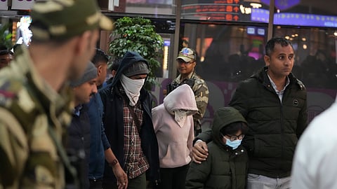 Indian police officials escort immigrants, wearing mask, deported from the United States