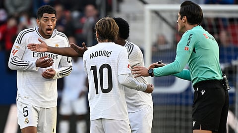 Real Madrid's Jude Bellingham (L) reacts to being presented a red card by Spanish referee Munuera Montero during the Spanish league football match between CA Osasuna and Real Madrid CF at El Sadar Stadium in Pamplona on February 15, 2025. 