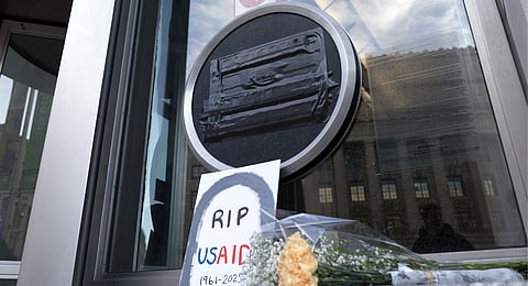 Flowers and a sign are placed outside the headquarters of the U.S. Agency for International Development, or USAID, Feb. 7, 2025, in Washington. 