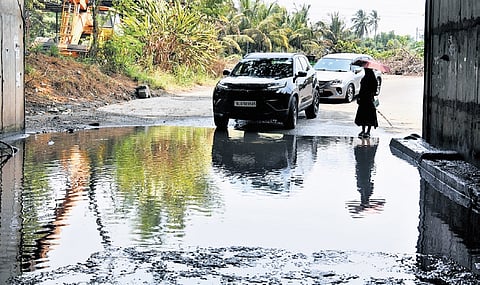 A pedestrian negotiating the waterlogged underpass which also witnesses a sizeable vehicle traffic 