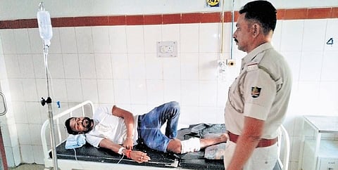 A policeman guards injured criminal Biyes Lakhua in hospital.