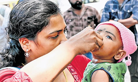 An ASHA worker cools down her child with fruits and water as she battles the scorching heat at the protest site on Saturday. ASHA workers have been protesting in front of the Secretariat for the past 36 days 