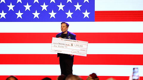 Elon Musk holds a check for $1 million dollars at a town hall Sunday, March 30, 2025