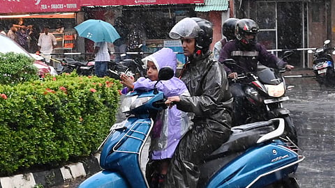 A mother and child riding a scooter during mild rain in Thiruvanathapuram.