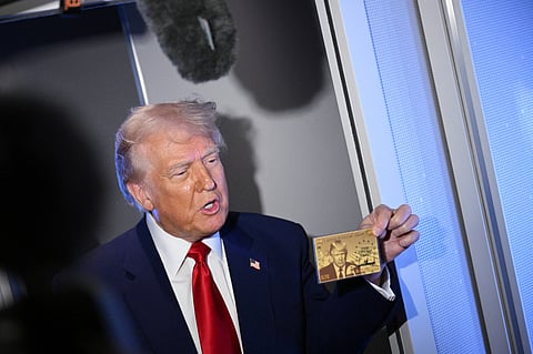 US President Donald Trump holds the $5 million dollar Gold Card as he speaks to reporters while in flight on board Air Force One, en route to Miami, Florida on April 3, 2025. Trump is travelling to the Trump National Doral Golf Club before going to his Mar-a-Lago Resort. 