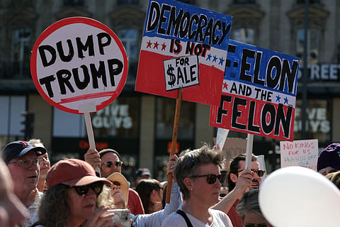 Protesters hold placards during a "Hands Off!" demonstration called by the Democrats Abroad organisation against US President's administration and his advisor Tesla CEO in Paris, on April 5, 2025.