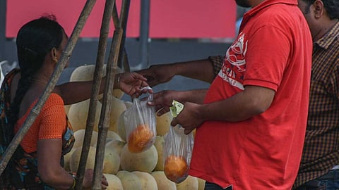 A woman gives fruits in a single use plastic bag. 