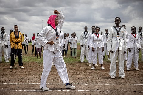 A young refugee demonstrates taekwondo moves as other girls watch during a showcase performance at a sports day event at the Kalobeyei Sports Complex in Kalobeyei on March 28, 2025. 