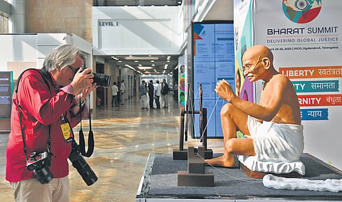 A foreign delegate captures a photograph of a Mahatma Gandhi sculpture, showcased at Bharat Summit 2025 at HICC in Hyderabad 
