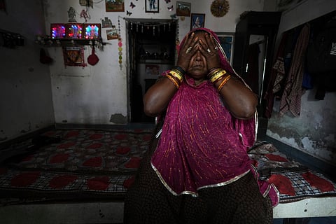 Shantaben Vanzara, wearing a wristwatch-style health monitor to study how heat affects vulnerable communities, wipes her face inside her house in Ahmedabad.