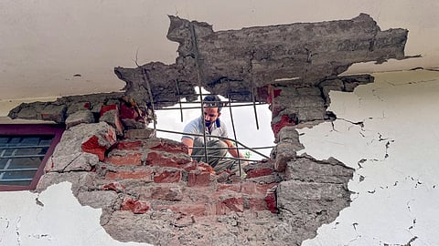 A man looks through a damaged portion of a house after heavy firing and shelling by the Pakistan military overnight across the Line of Control and International Border in the Mendhar area of the Poonch district, Jammu.
