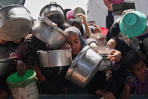 Palestinians struggle to get donated food at a community kitchen in Khan Younis, Gaza Strip, Monday, May 5, 2025. 