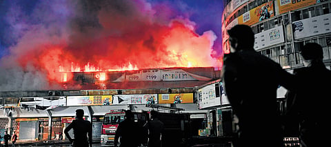 Fire rages at a commercial building near the Mofussil Bus Stand in Kozhikode on Sunday as fire and rescue services personnel try to douse the flames.