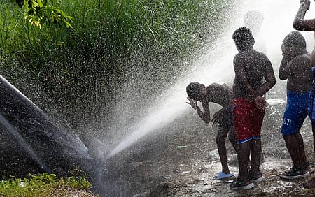  Boys enjoying drinking water main pipeline leakage under the Mysuru Road service area on Friday