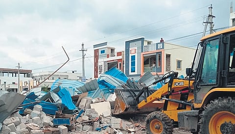 An earthmover clears encroachments on cemetery land in Parvathpur
