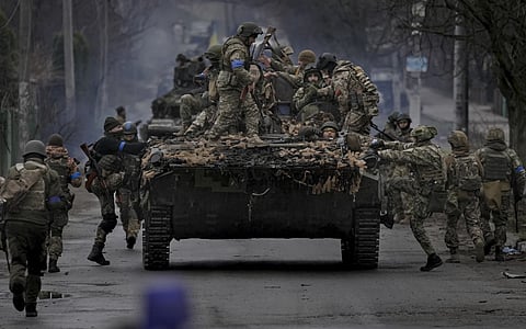 Ukrainian servicemen climb on a vehicle outside Kyiv, Ukraine, on April 2, 2022.