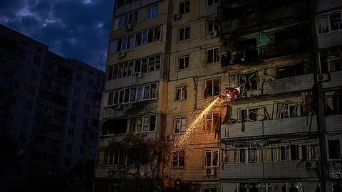 Firefighter clear debris from a balcony at a residential building damaged after a Russian attack in Kyiv, Ukraine, Saturday, May 24, 2025 