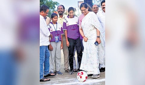 Dr Kavitha Reddy smiles as she plays football, surrounded by officials and kids, during a programme by the Health Foundation, which is actively promoting the sport.