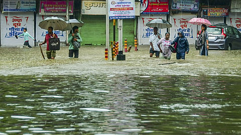 Mumbai: Pedestrians wade through an inundated road amid rains, in Mumbai, Monday, May 26, 2025.