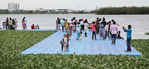 A large number of people are seen walking over the unfinished floating jetty arrangement in Vandiyur Kanmoi in Madurai. 