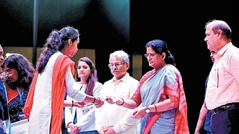 Parida giving a reusable sanitary napkin to a girl at the event 