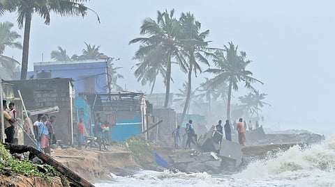 Fisherfolk anxiously watch the waves crashing onto the shore at Mambally near Anchuthengu in Thiruvananthapuram. Fishermen across the state have been banned from going to the sea due to the heavy rain.