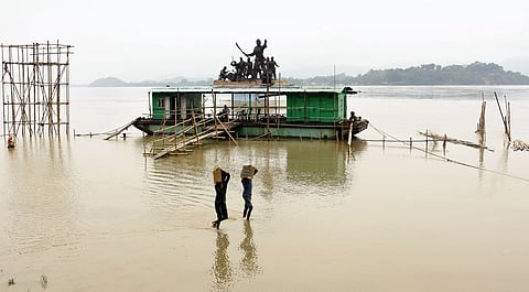 In this image from 2024, people are seen walking through the flooded riverbanks of Brahmaputra at Kasomari Ghat in Guwahati as Brahmaputra river and its tributaries flowed above the danger level marks at many places in the state after incessant rains in Assam and Arunachal Pradesh. 