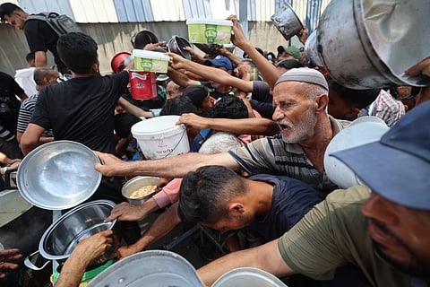 Palestinians queue up for food at a distribution point in Nuseirat, in the central Gaza Strip, on June 11, 2025. 
