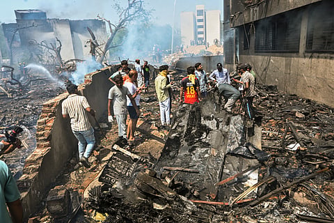 People stand near the debris of the Air India plane that crashed moments after taking off from the airport, in Ahmedabad, Thursday, June 12, 2025. 