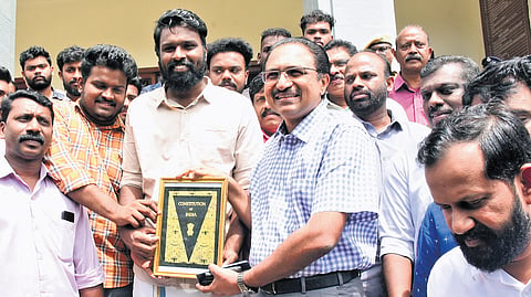 SFI workers present a copy of the Constitution to suspended Kerala University registrar K S Anil Kumar at the university headquarters on Thursday 