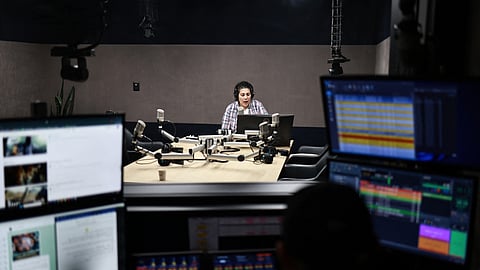 Hiba Eriqat, a host for the Palestinian radio show "Traffic on the Road," speaks into the microphone to update listeners on road status and checkpoints in the Israeli-occupied West Bank at the Basma Radio station headquarters in Rawabi, north of Ramallah, on June 10, 2025. 