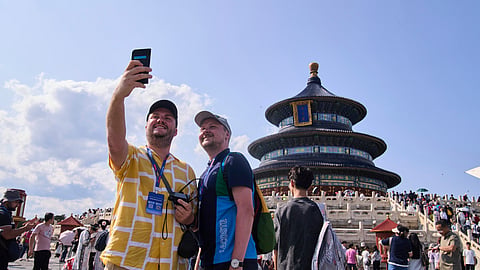 Tourists take a selfie at the Temple of Heaven as they take a half-day tour offering by a travel agency Trip.com Group, in Beijing on June 15, 2025. 
