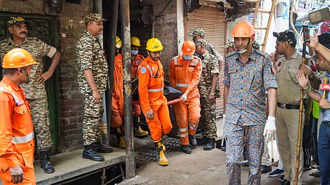 NDRF personnel carry a recovered body during a rescue operation after a four-storey building collapsed at Welcome area.