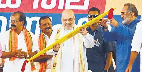 Union Home Minister Amit Shah looks at an ‘Onavillu’ (ceremonial bow) presented to him ahead of the party workers’ meeting at Putharikandam ground in Thiruvananthapuram on Saturday 