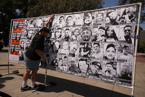 A volunteer sets up an art installation displaying names and faces of people who have been detained, deported, or sent to offshore camps during ICE raids in Southern California, at Olvera Street Plaza in Los Angeles, on Thursday, July 3, 2025.