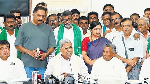 Chief Minister Siddaramaiah announces that the state government has withdrawn the land acquisition bid in Channarayapatna, Devanahalli taluk, as his cabinet colleagues and farmer activists look on, in Bengaluru on Tuesday 