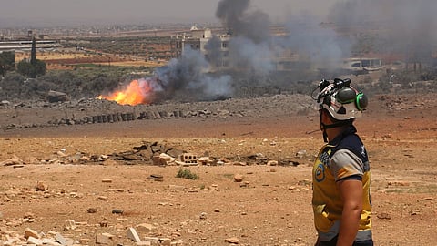 In this photo provided by the Syrian Civil Defense White Helmets, a Syrian Civil Defense worker checks the explosion scene in Maarat Misrin village, in Idlib province, north Syria, Thursday, July, 24, 2025.
