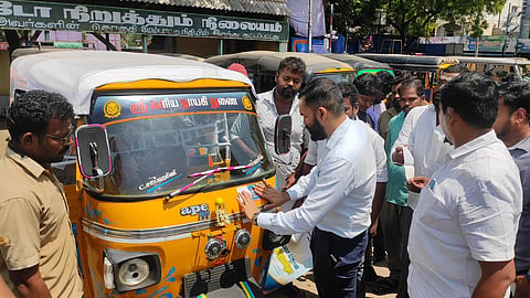 District Collector P Akash sticking the promo sticker on an auto rickshaw at the auto stand near the Perarignar Anna Bus Stand in Velippalayam in Nagapattinam to promote the upcoming fourth book fair in the district to the public.
