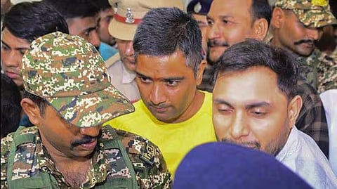 Security personnel and others escort Chaitanya Baghel (in yellow), the son of former Chhattisgarh CM Bhupesh Baghel, after his arrest by the Enforcement Directorate on July 18.