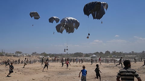 Palestinians rush to collect humanitarian aid airdropped by parachutes into Zawaida in the central Gaza Strip, Monday, Aug. 4, 2025.