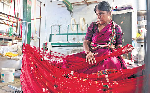 A weaver works on an Asu frame at Pochampally while weaving sarees on the eve of National Handloom Day on Wednesday.