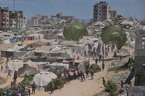 Palestinians rush to collect humanitarian aid airdropped by parachutes into Gaza City, northern Gaza Strip, Thursday, Aug. 7, 2025.