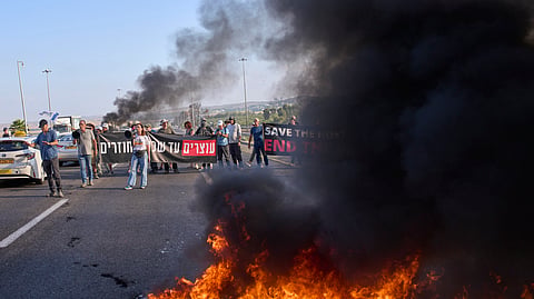 Demonstrators block a road during a protest demanding the immediate release of hostages held by Hamas and calling for the Israeli government to reverse its decision to take over Gaza City and other areas in the Gaza Strip, near Jerusalem, Israel, Sunday, Aug. 17, 2025