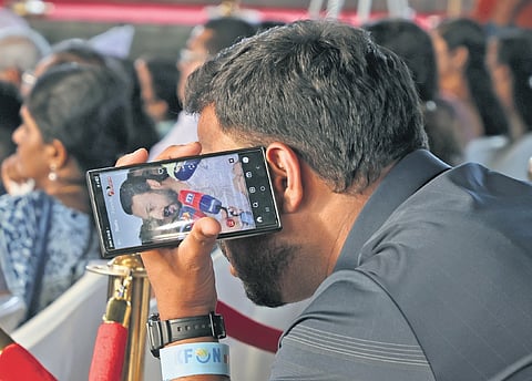 A person attending the launch of K-FON OTT services at Nishagandhi auditorium in Thiruvananthapuram on Thursday, keenly listening to reports related to Rahul Mamkoottathil’s resignation 